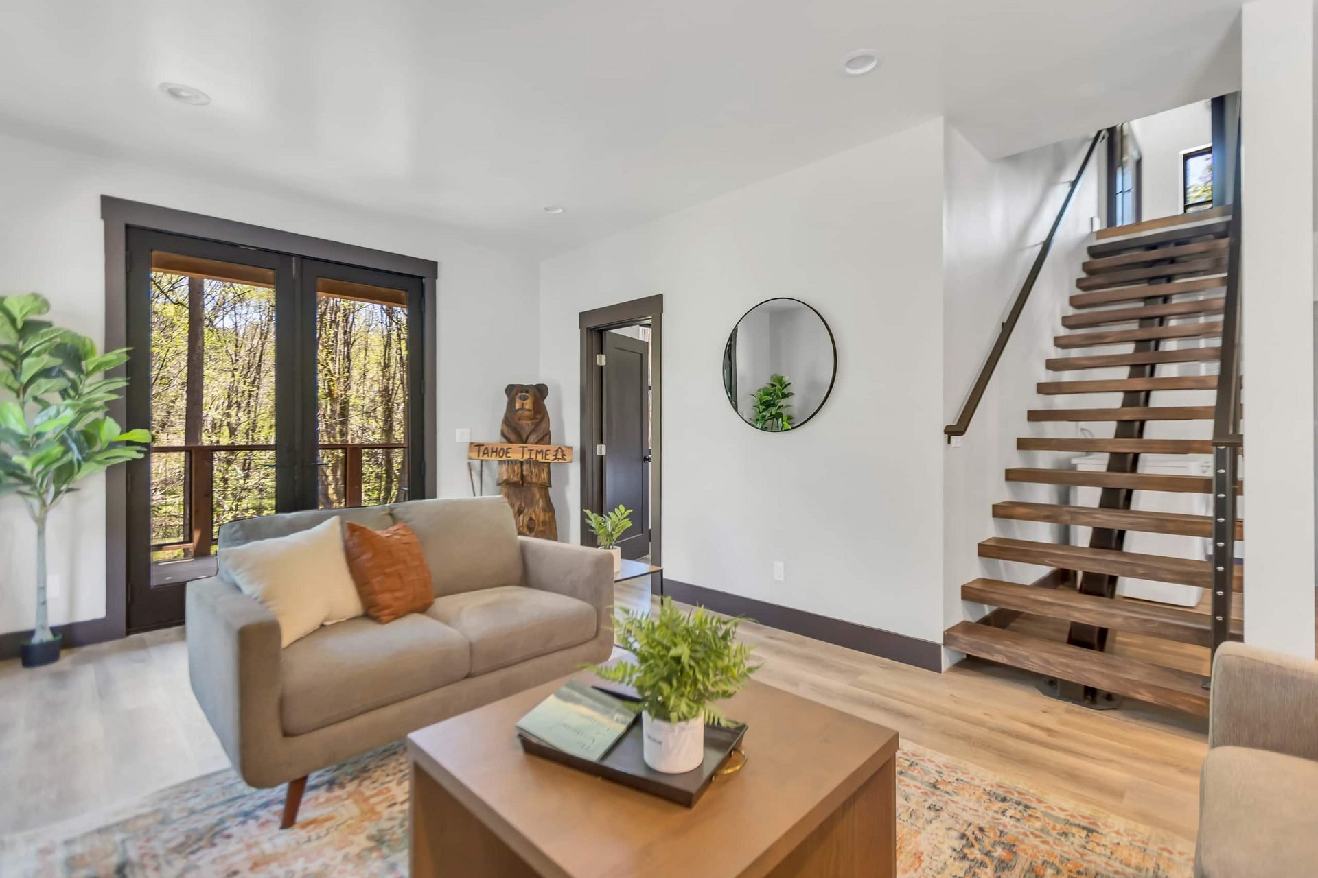 Lower living room with loveseat, open staircase and French doors to the deck